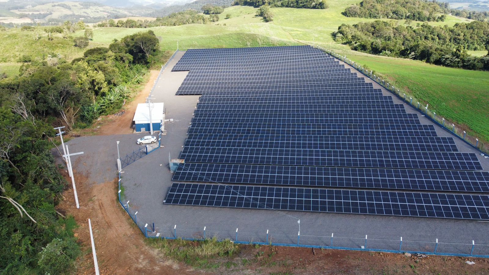 Grande instalação de painéis solares em área verde ondulada